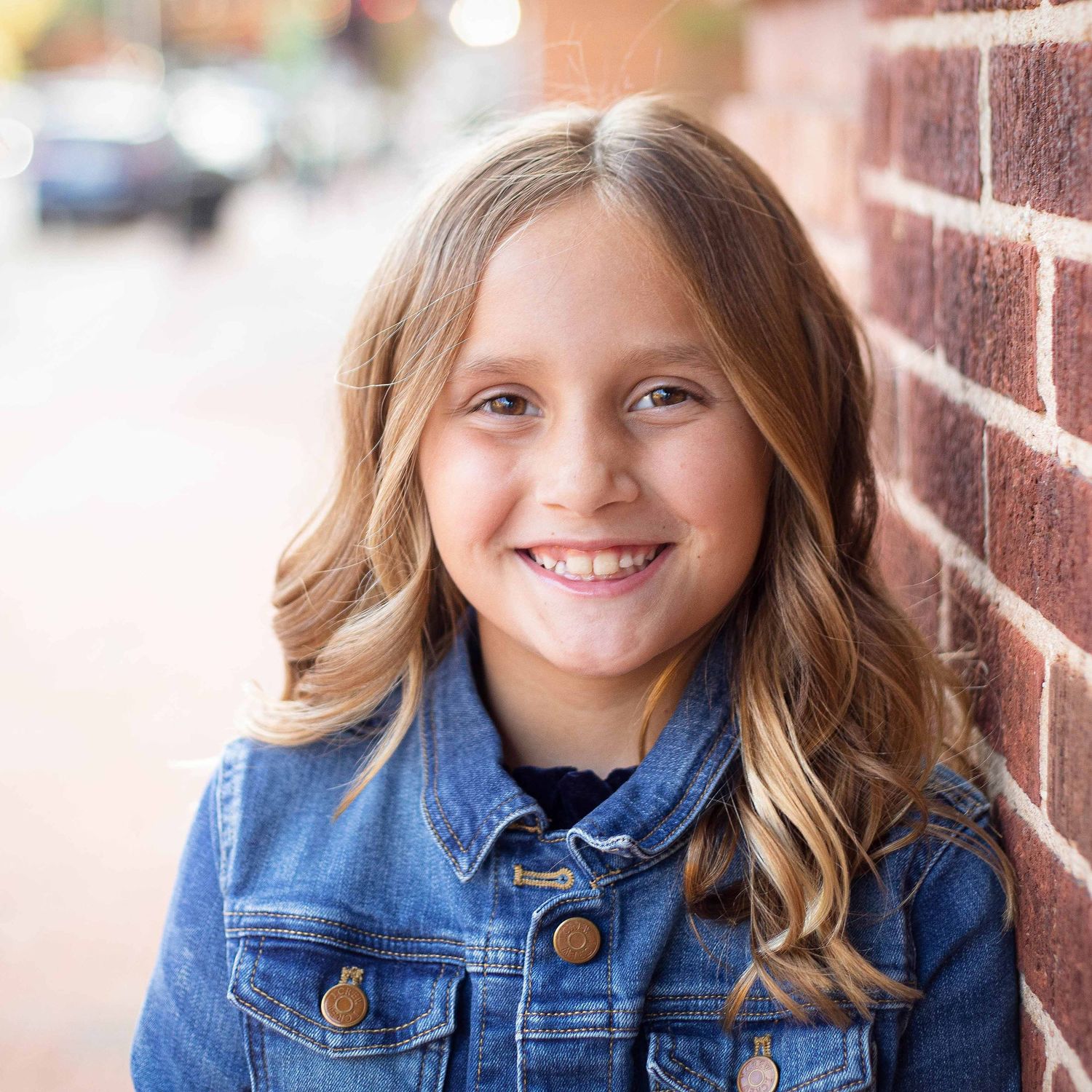 little girl smiling against a brick wall by victoria leigh photography