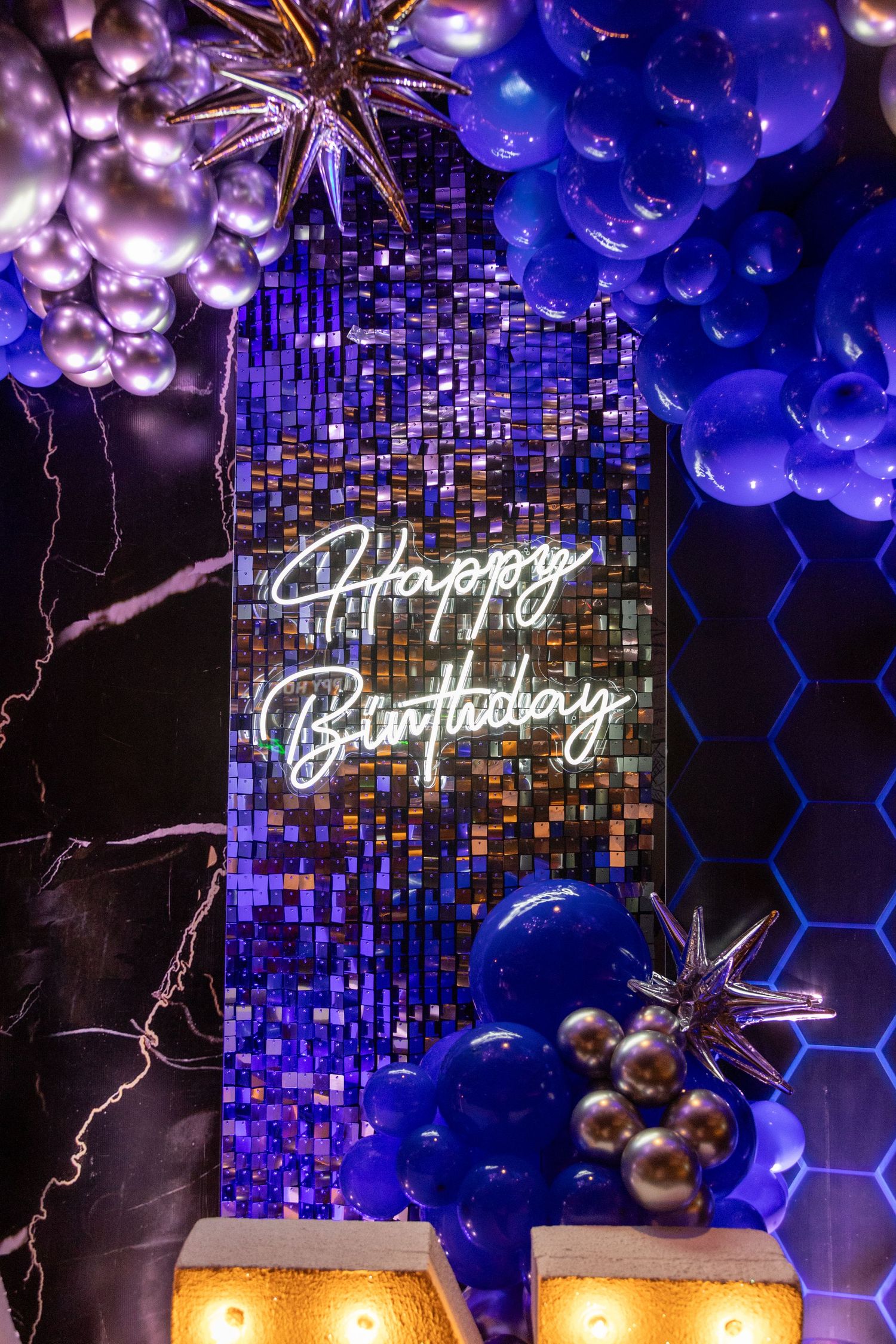 Elegant birthday decor featuring blue and purple balloons with neon Happy Birthday sign.