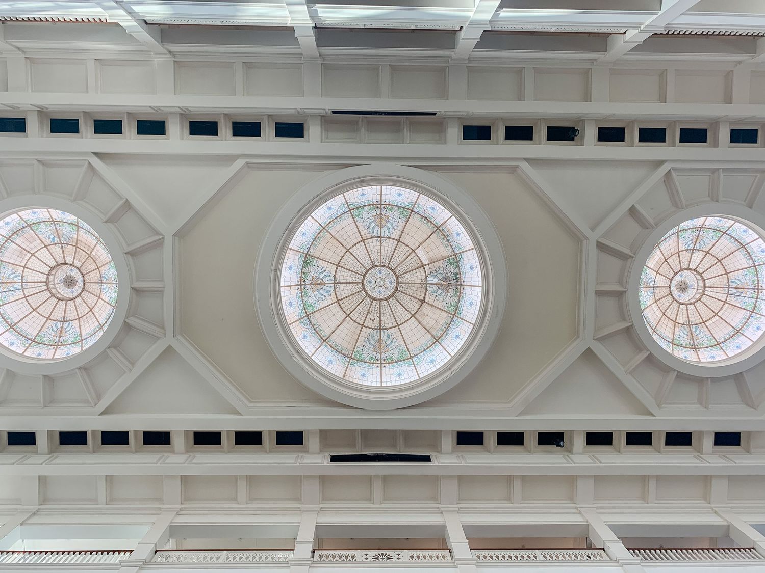 Elegant ceiling architecture with decorative stained glass circular windows and geometric patterns.