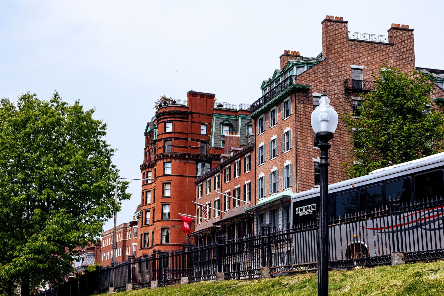 Historic brick buildings with red facades line a street under blue skies.