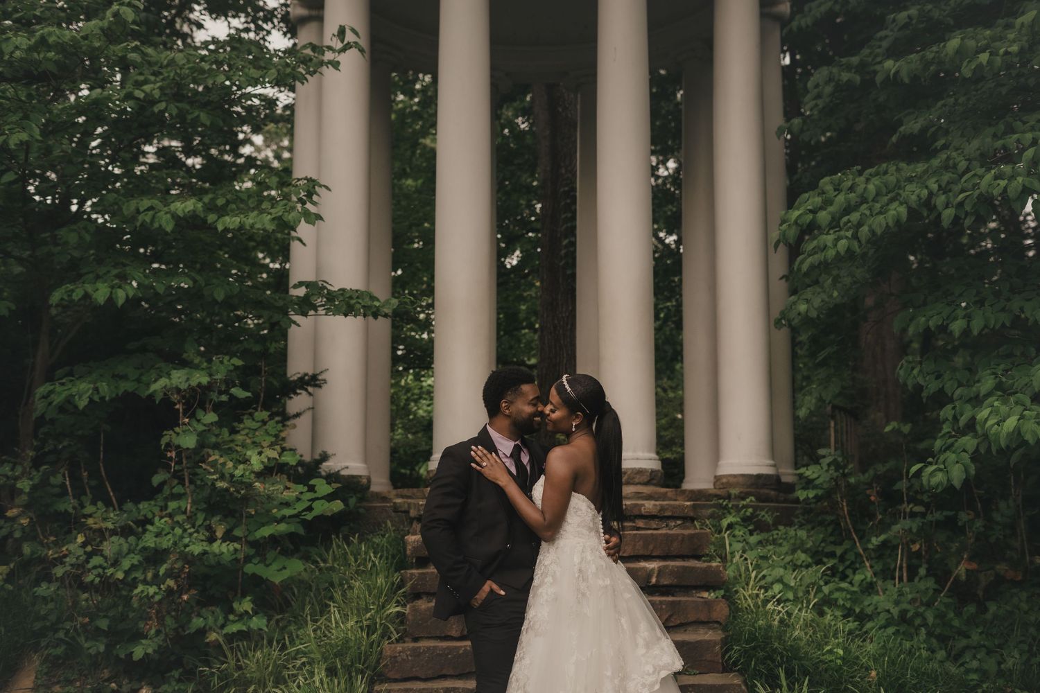 a bride and a groom smiling at each other while standing in front of tall white columns