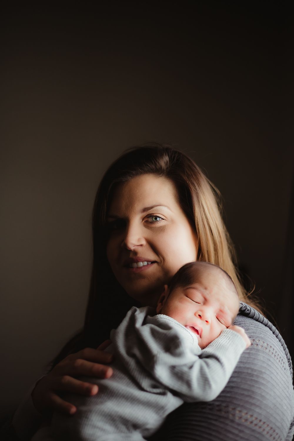 Mom holding her newborn baby on her chest during a lifestyle newborn session