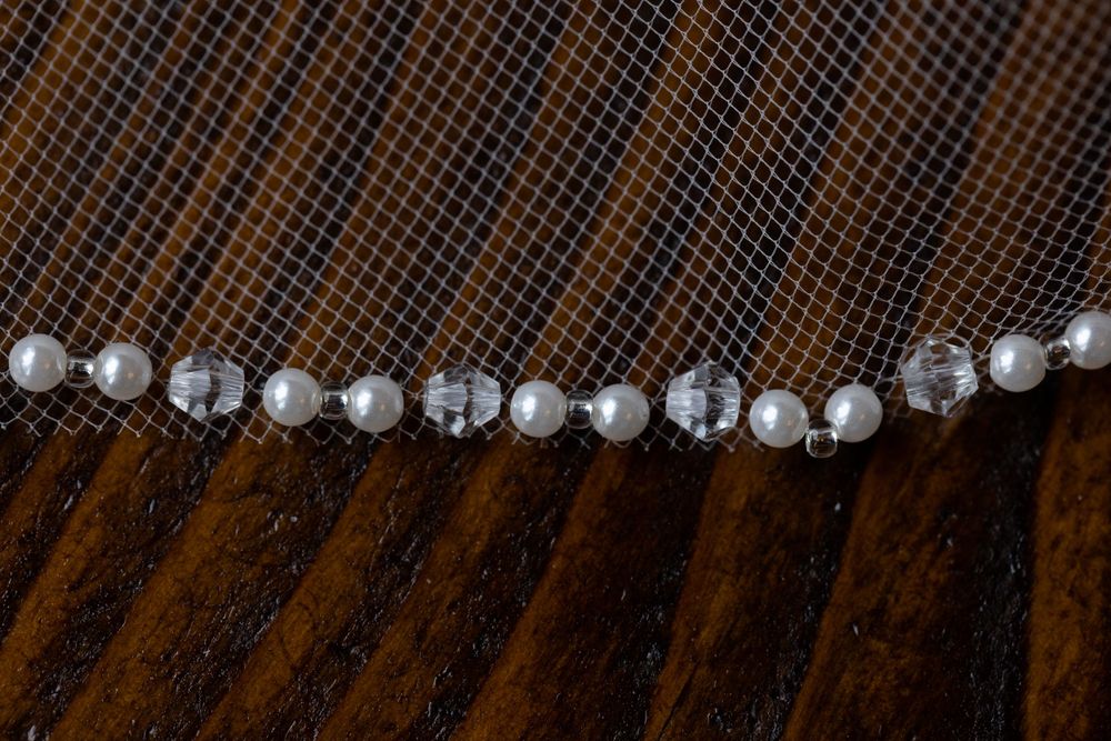 Pearl and crystal bridal hair accessory displayed on dark wooden surface.