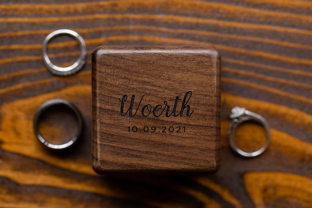 Wooden ring box engraved with 'Wierth' and wedding date surrounded by wedding bands.