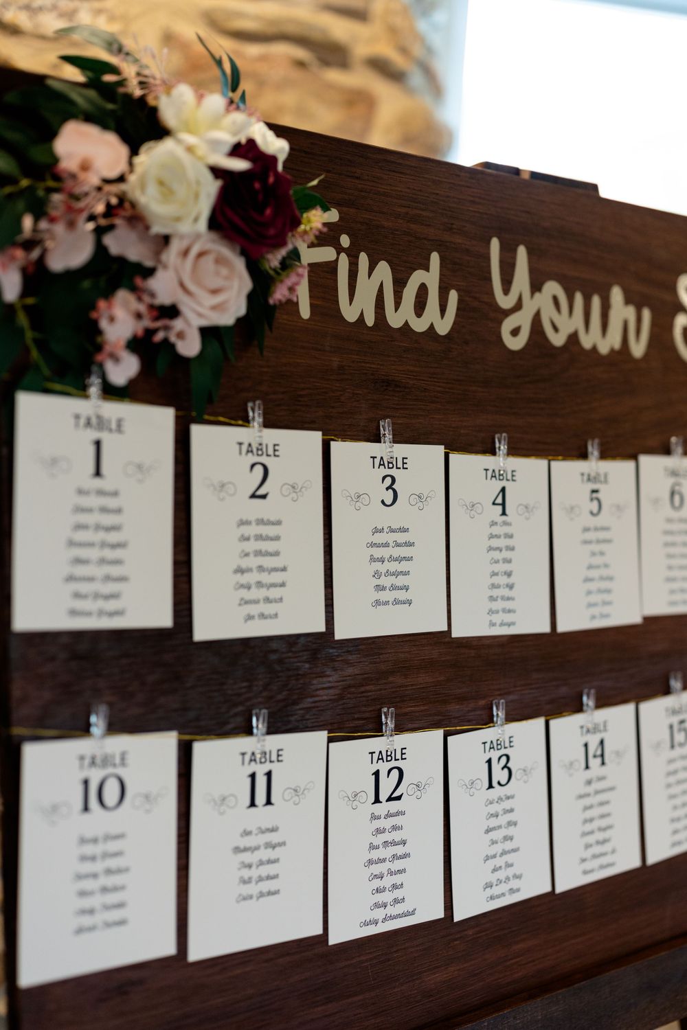 Wooden seating chart display with 'Find Your' text and numbered table cards.