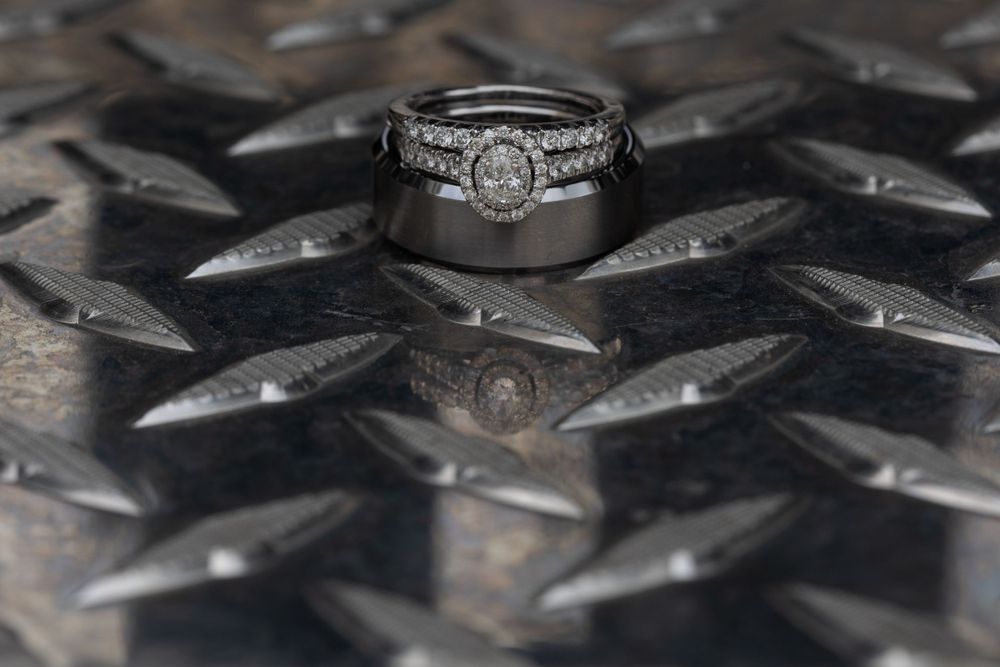 Wedding rings photographed on a diamond plate metal surface with dramatic lighting.