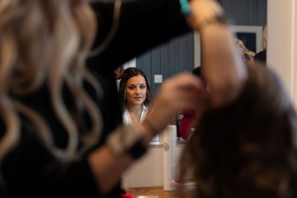 A mirror reflection shows someone applying makeup in soft focus.