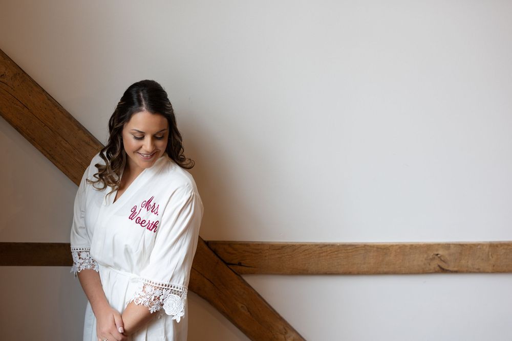 Person in white robe stands against wall with wooden beam detail.