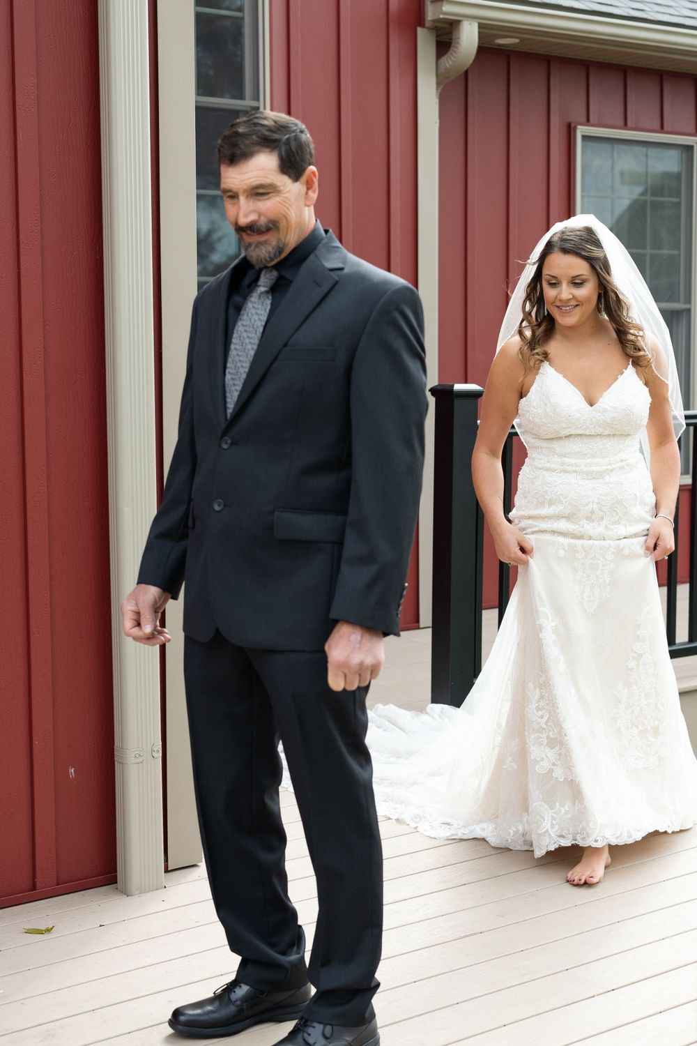 Wedding first look scene on deck with red building backdrop.