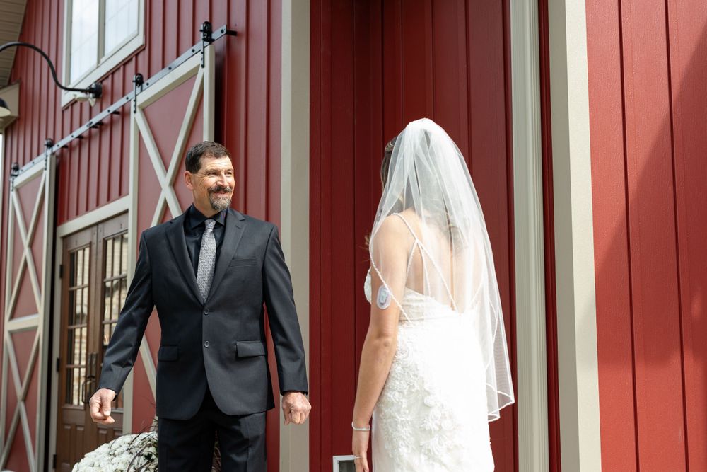 First look moment between couple outside red barn building.