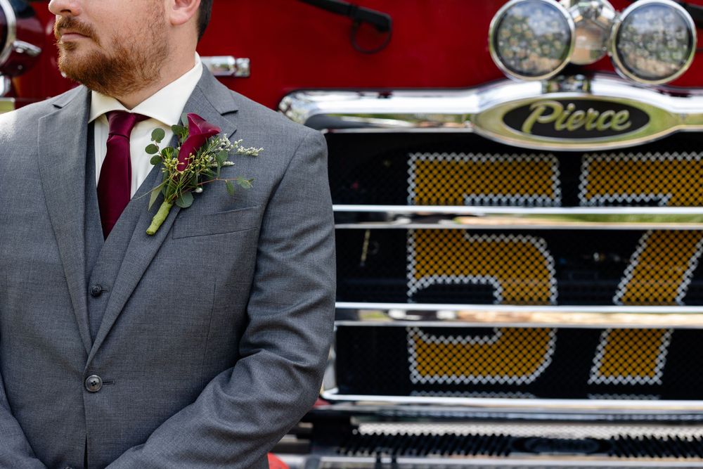 Close-up detail of grey suit and burgundy tie against red fire truck background.