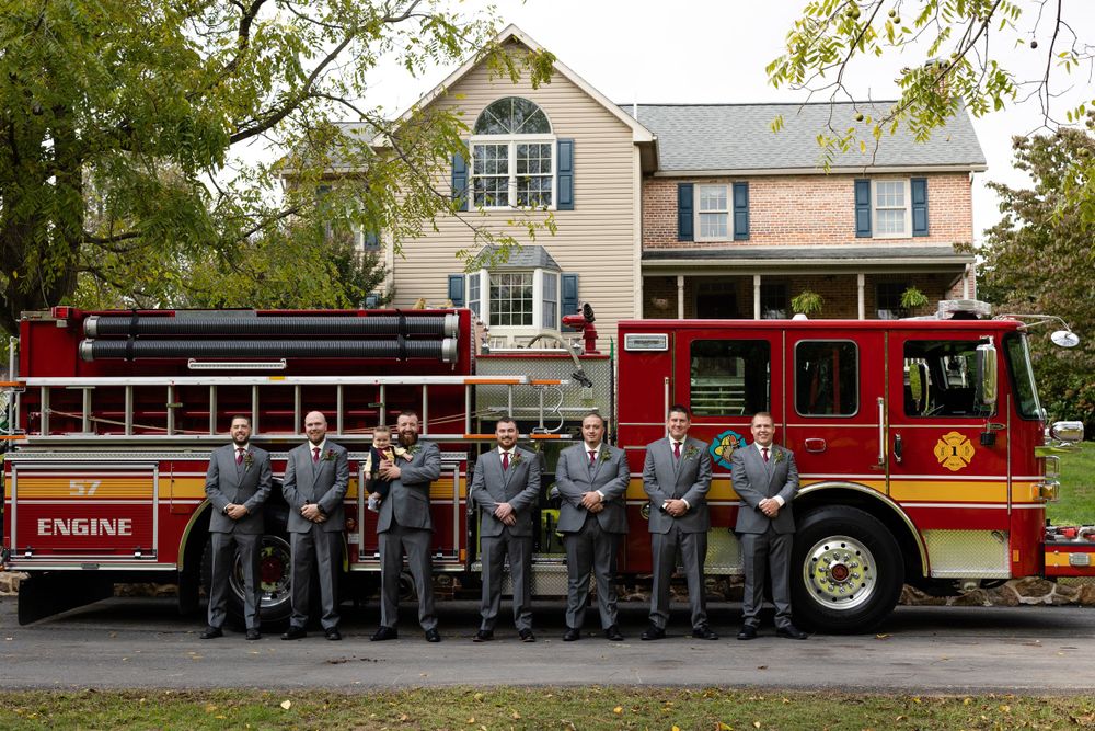 Wedding party group photo in front of a vintage red fire truck parked in front of a classic house.