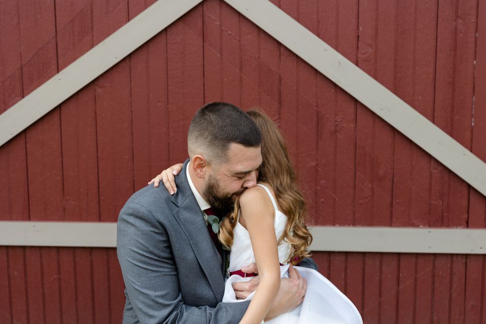 Romantic moment captured against a red barn backdrop with white trim.
