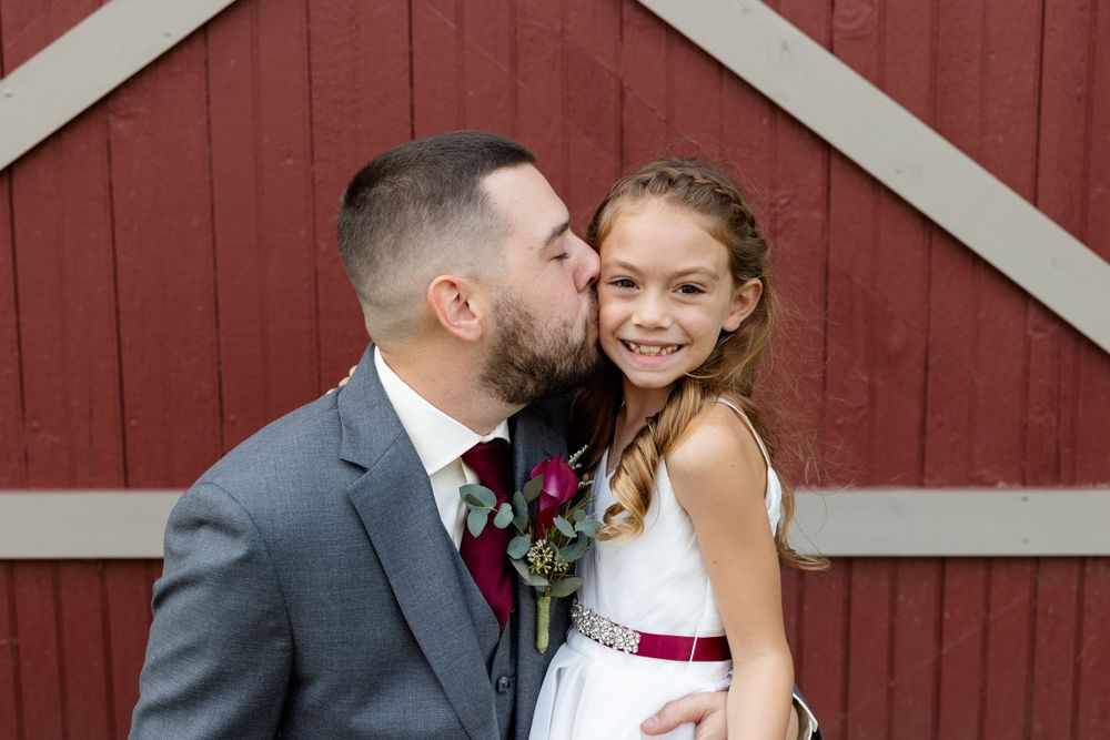Sweet moment shared against rustic red barn background.
