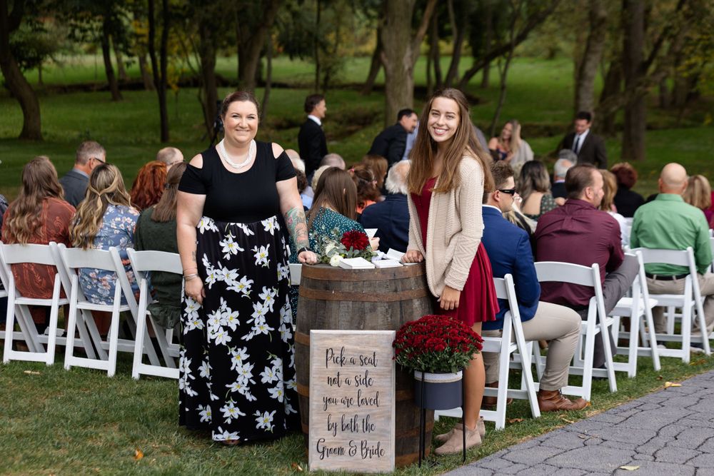 Outdoor wedding ceremony setup with wooden seating sign and white folding chairs.