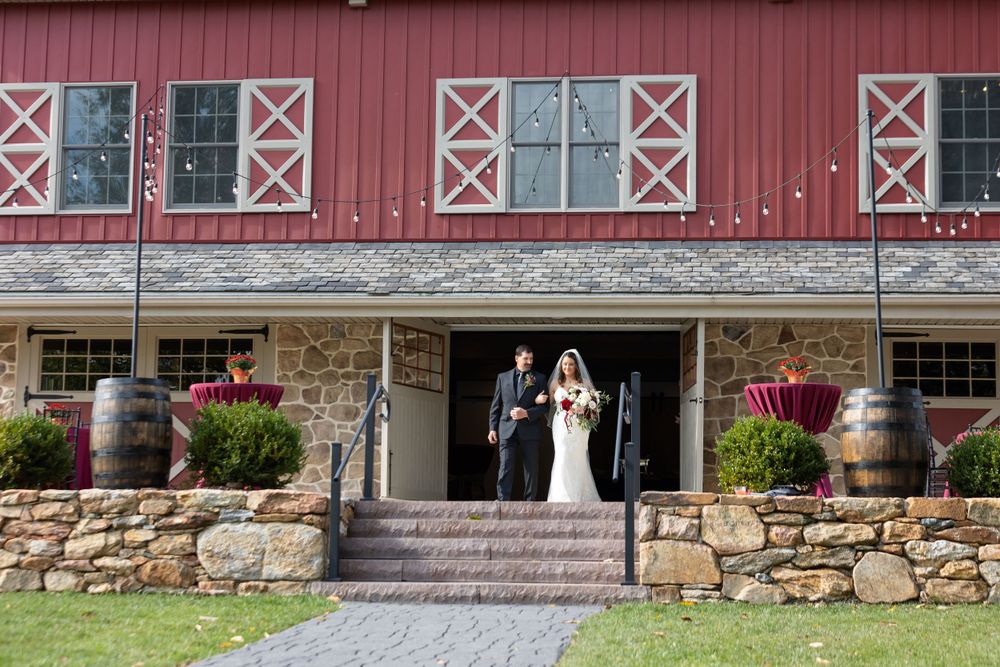 Red barn wedding venue exterior with stone foundation and white trim windows.