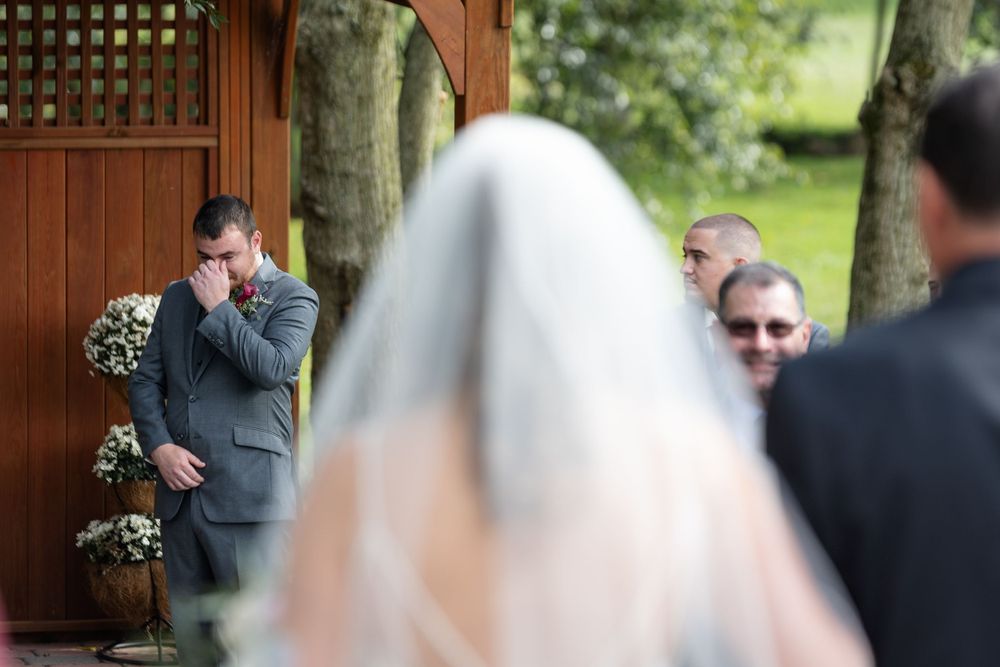 Emotional wedding ceremony moment at wooden gazebo.