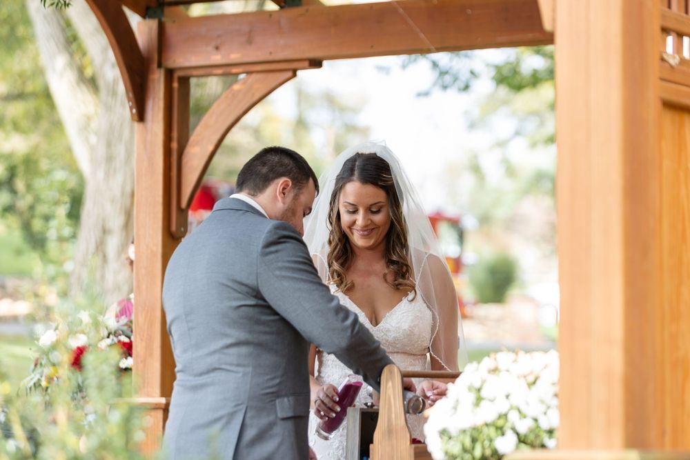Wedding ceremony moment under wooden pergola with floral decorations.