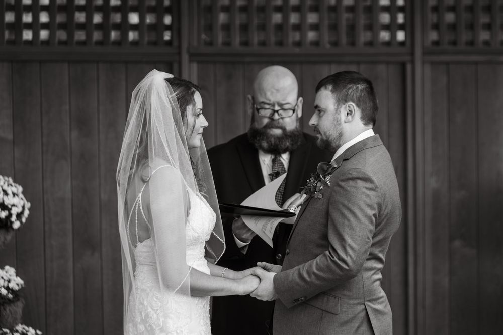 Black and white wedding ceremony photo at wooden venue.
