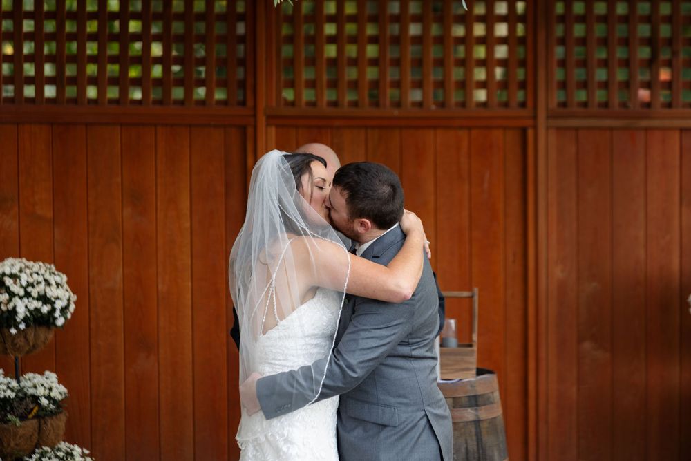 Romantic moment during wedding ceremony in wooden gazebo with lattice backdrop.