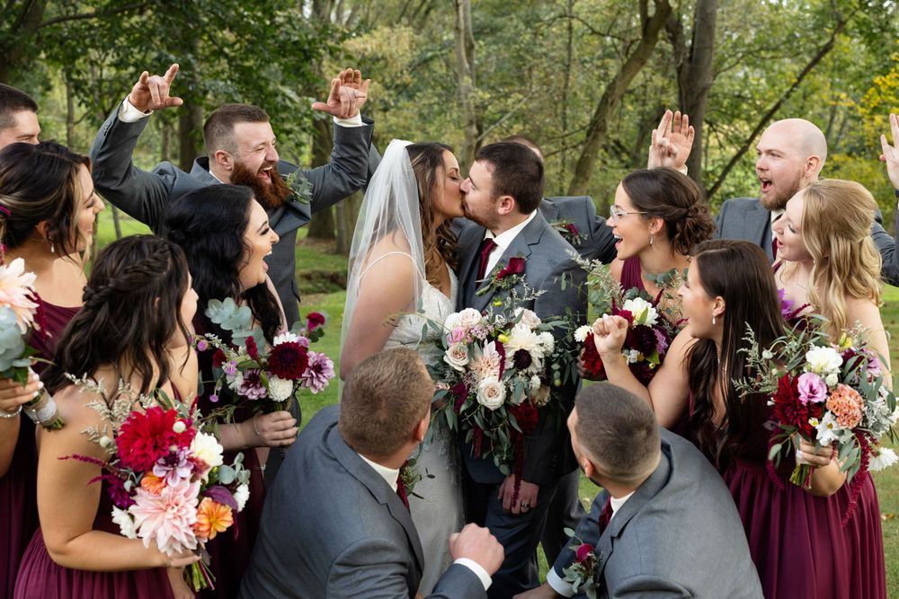 Wedding party celebrates with drinks and flowers in outdoor garden setting.