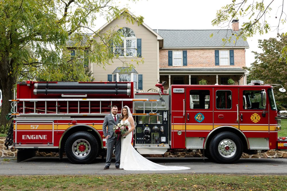 A couple celebrates their wedding with a bright red fire engine as their backdrop.