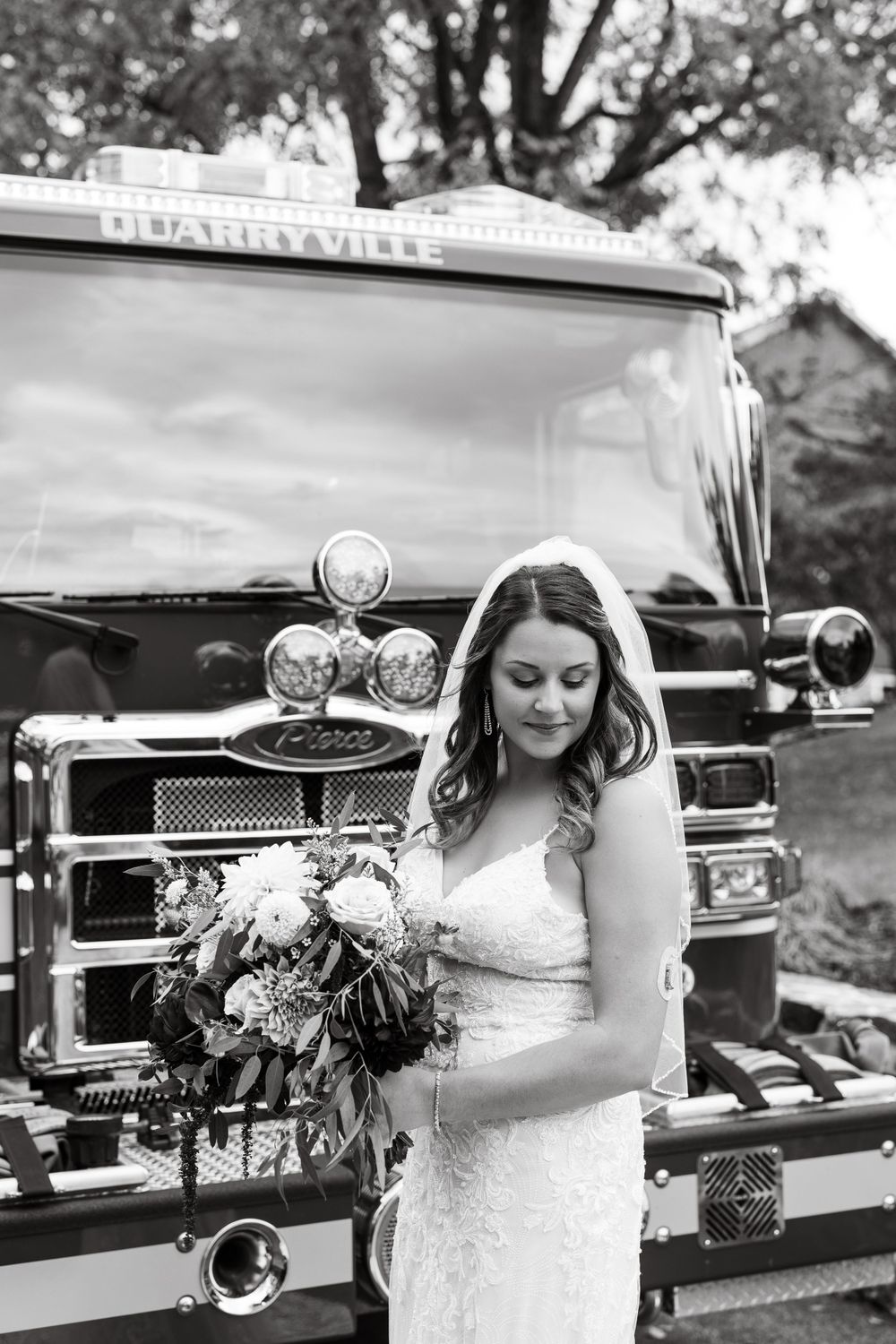 A bride with a stunning bouquet poses in front of a Blairsville fire truck in black and white.
