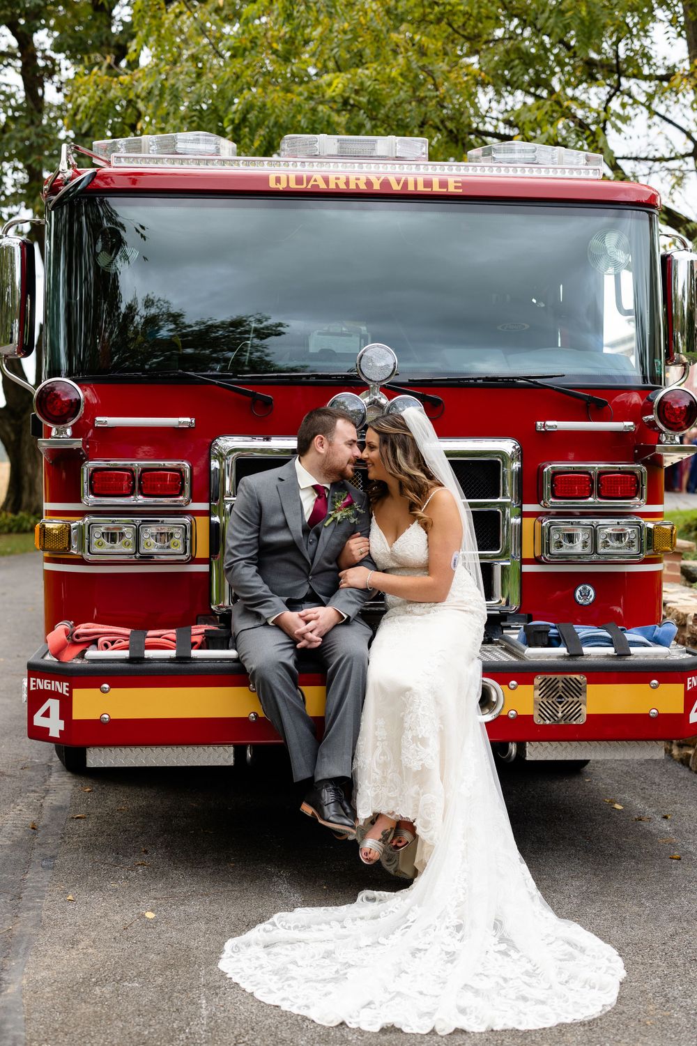 Newlyweds share an intimate moment while seated on the front of a fire truck.