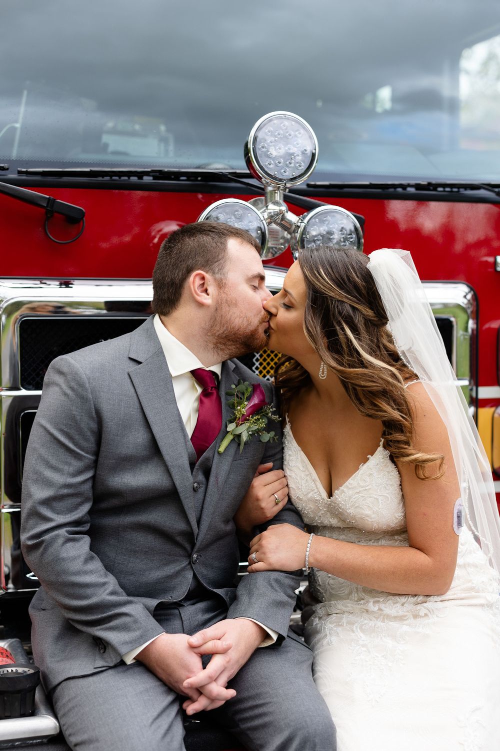 A romantic moment shared in front of a vintage red fire truck.