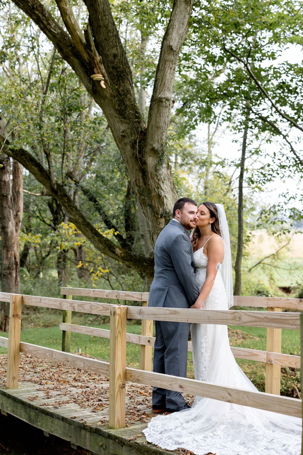 Romantic wedding portrait on wooden bridge surrounded by autumn trees.