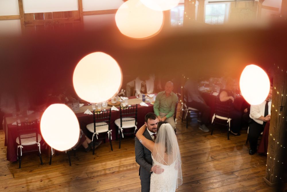 Couple dances at their reception with glowing white balloon lights creating a romantic atmosphere.