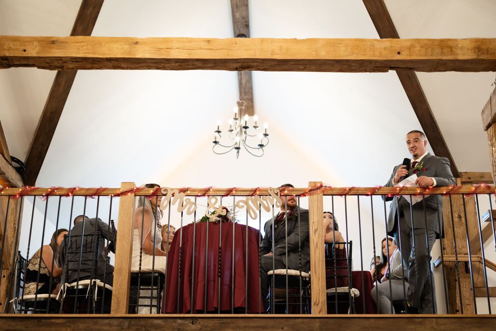 Musicians perform from a wooden balcony during a rustic barn wedding reception.