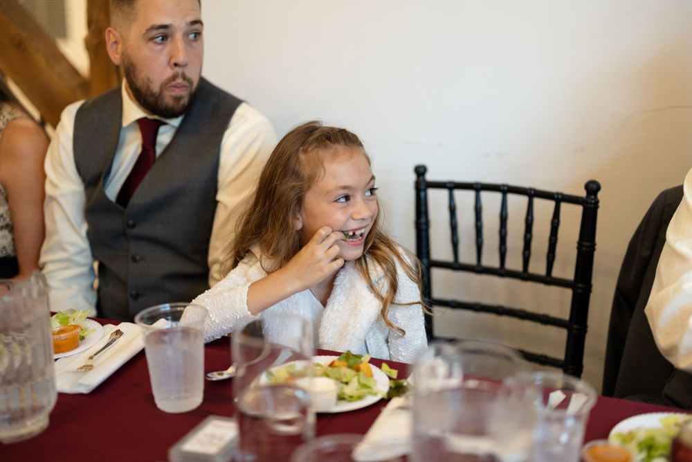Young guest enjoying dinner at a wedding reception table with burgundy linens.