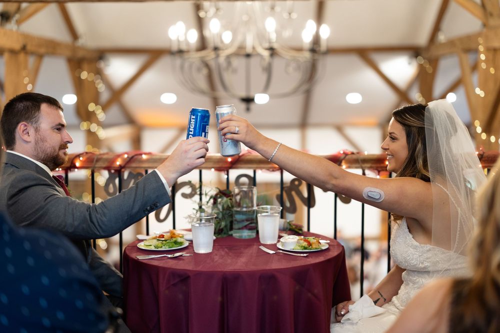 Bride and groom toast with blue drinks at their sweetheart table during the reception.