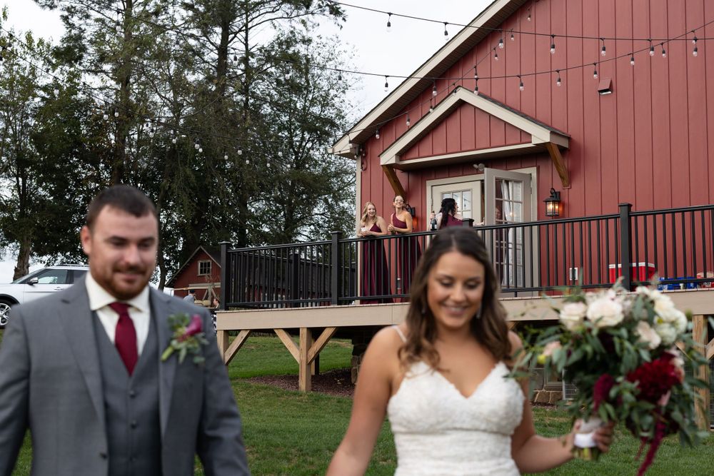 Red barn wedding venue with elevated deck and string lights against autumn trees.