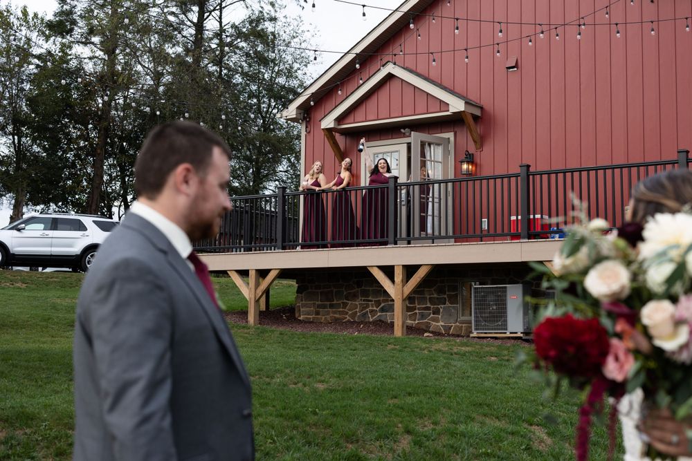 Rustic red barn wedding venue with stone foundation and elegant floral arrangements.