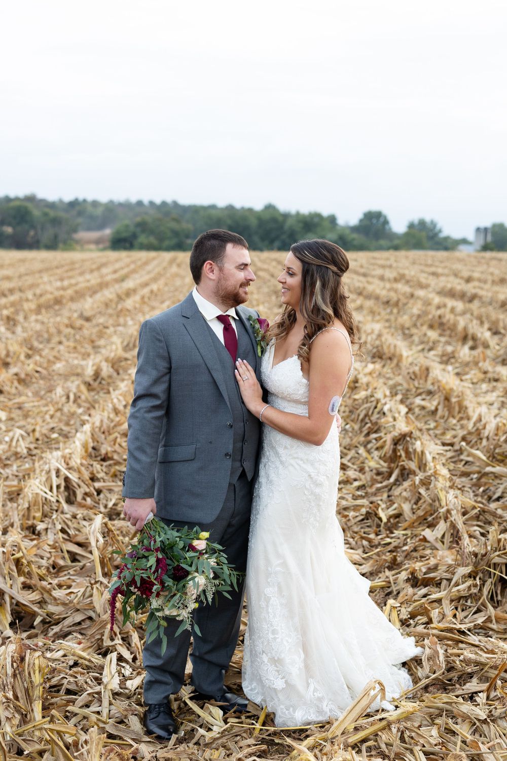 Wedding portrait in harvested cornfield with overcast sky creating dreamy atmosphere.