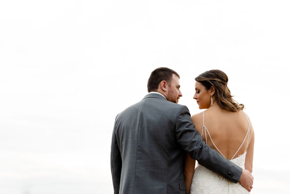 Intimate back-view portrait of couple against overcast sky on their wedding day.