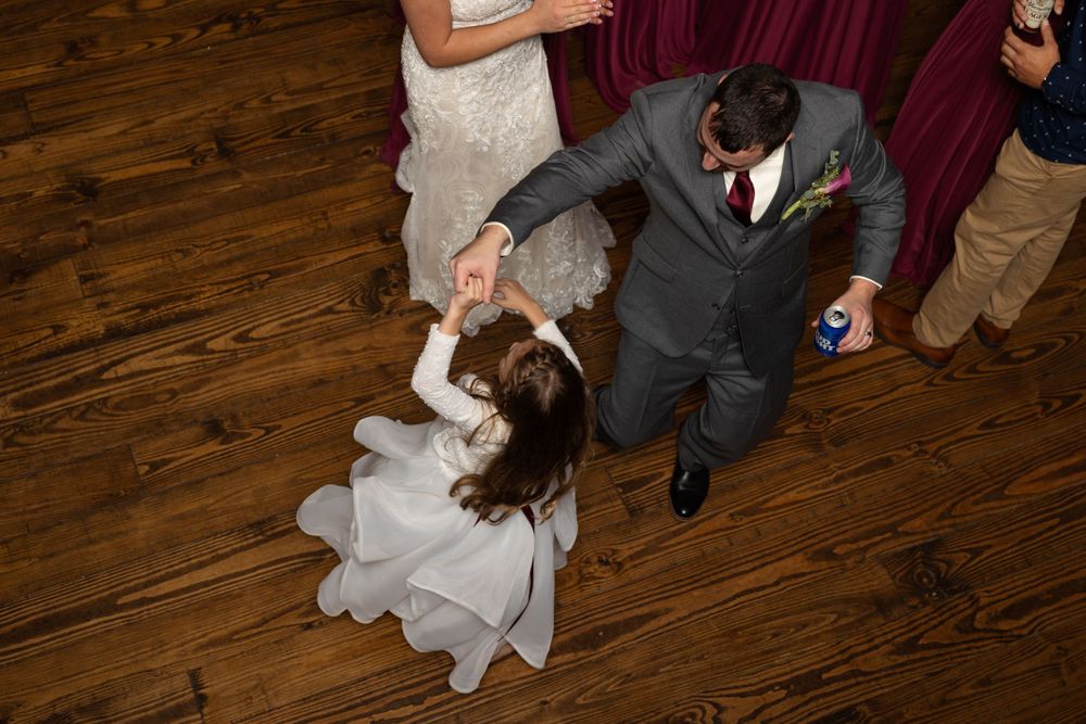 Wedding dance move captured on a wooden dance floor during reception celebrations.