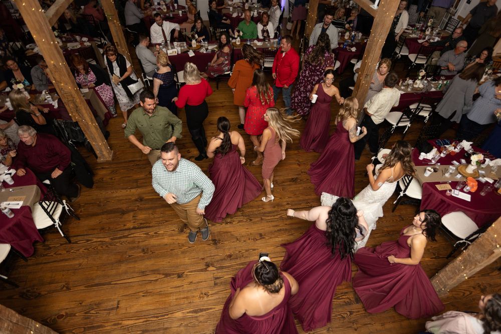 Overhead view of wedding guests dancing on a wooden floor during a lively reception.