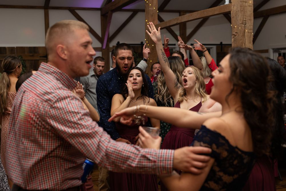 Energetic dancing and celebration at a wedding reception in a rustic venue.