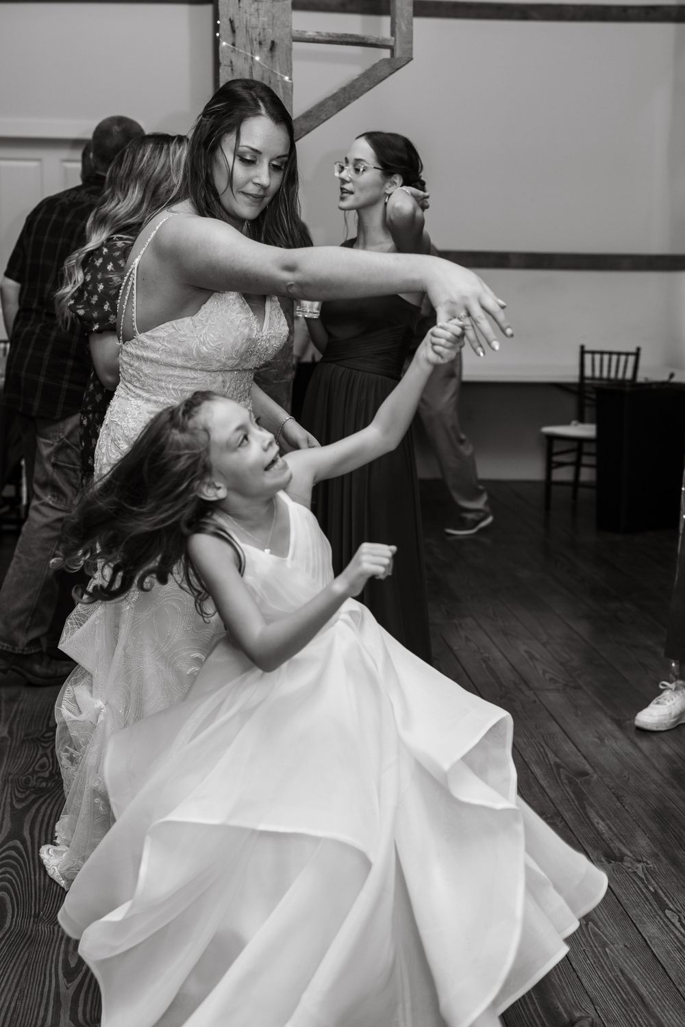 Dancing and twirling in white dresses at a joyful wedding celebration.
