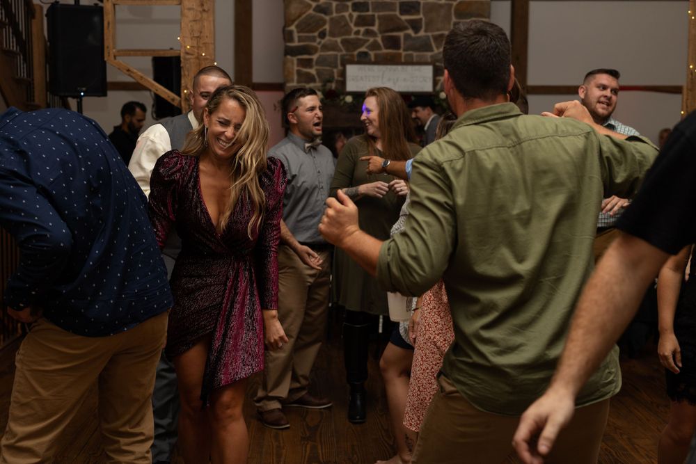 Party guests dancing and socializing at an evening event in a rustic venue.