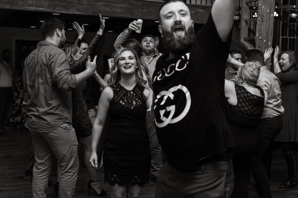 Black and white photo of energetic dancing at a party with people raising their arms in celebration.
