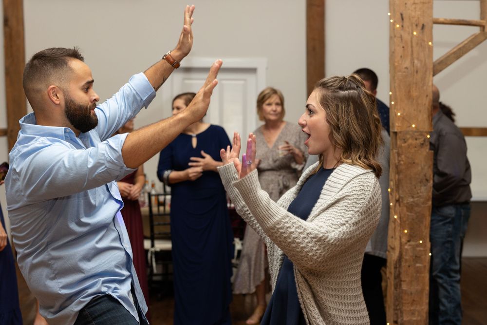 Guests dancing enthusiastically with raised arms during a lively wedding reception in a rustic venue.