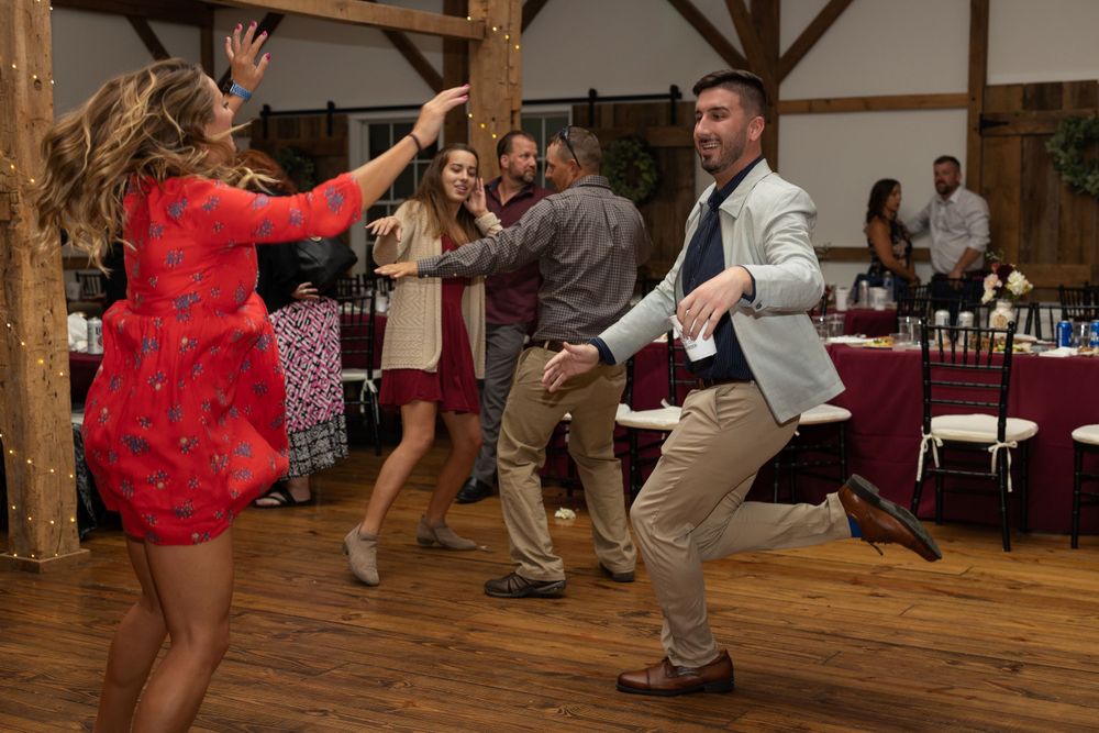 Wedding guests dancing and having fun on wooden dance floor at reception.