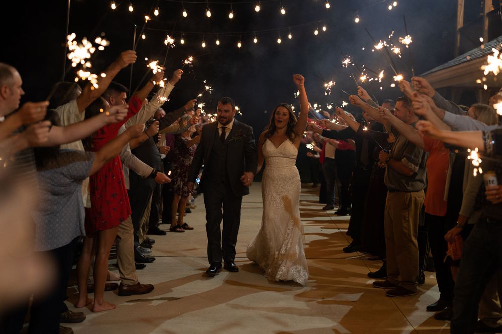 Wedding sparkler exit with couple walking through glowing tunnel of guests.