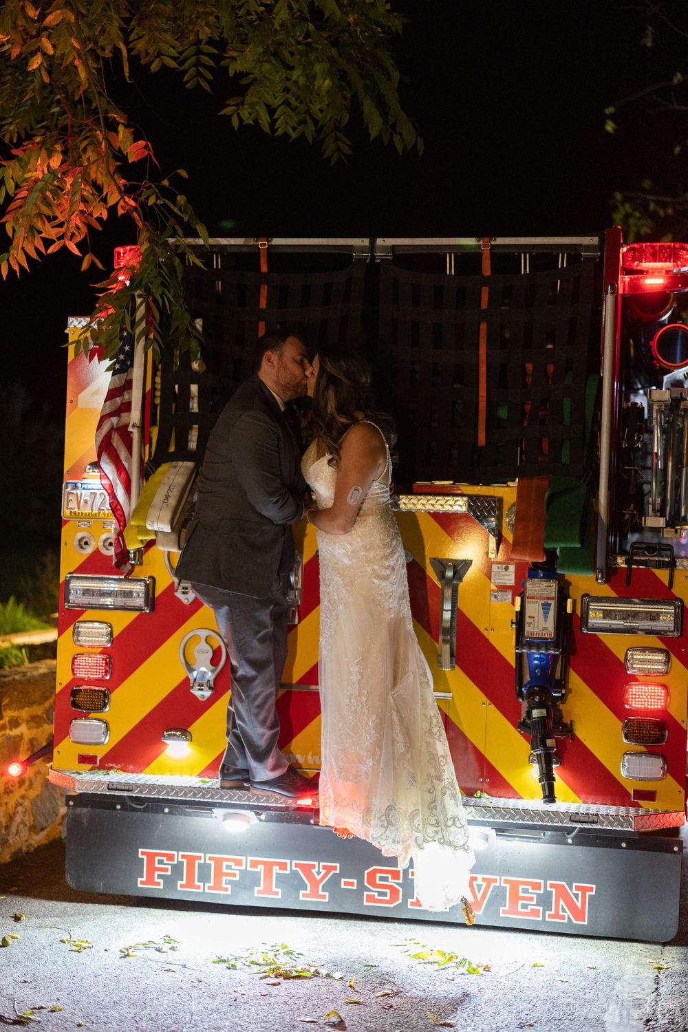 Wedding couple shares an intimate moment on a colorfully lit carnival game platform at night.