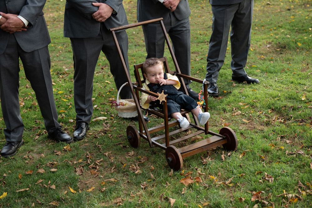 A small child rides in an antique push mower during a wedding photoshoot.