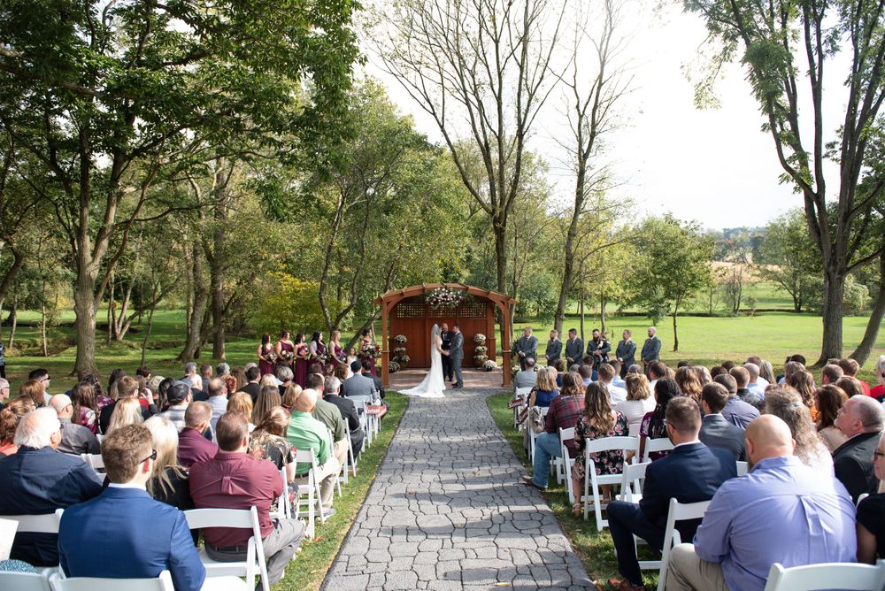Outdoor wedding ceremony with white chairs and wooden arch set up in a scenic park.